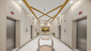 A modern hallway with elevators, numbered doors, and a central decorative floor pattern. - Golden Phoenix PEK Airport T3 Beijing (Beijing)