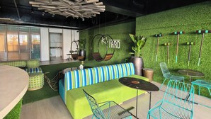 A modern lounge area with a green sofa, striped cushions, a round table, and blue chairs. - Isla Room by Lakbay Urban Living (Makati)
