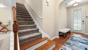 Un escalier avec des rampes en bois et des marches recouvertes de moquette, menant à un palier.