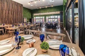 A spacious restaurant with multiple dining tables set for guests, featuring a modern interior with wooden accents and green walls. - 4 BR Home w/ Resort Amenities + 3 MI to Disney (Kissimmee)
