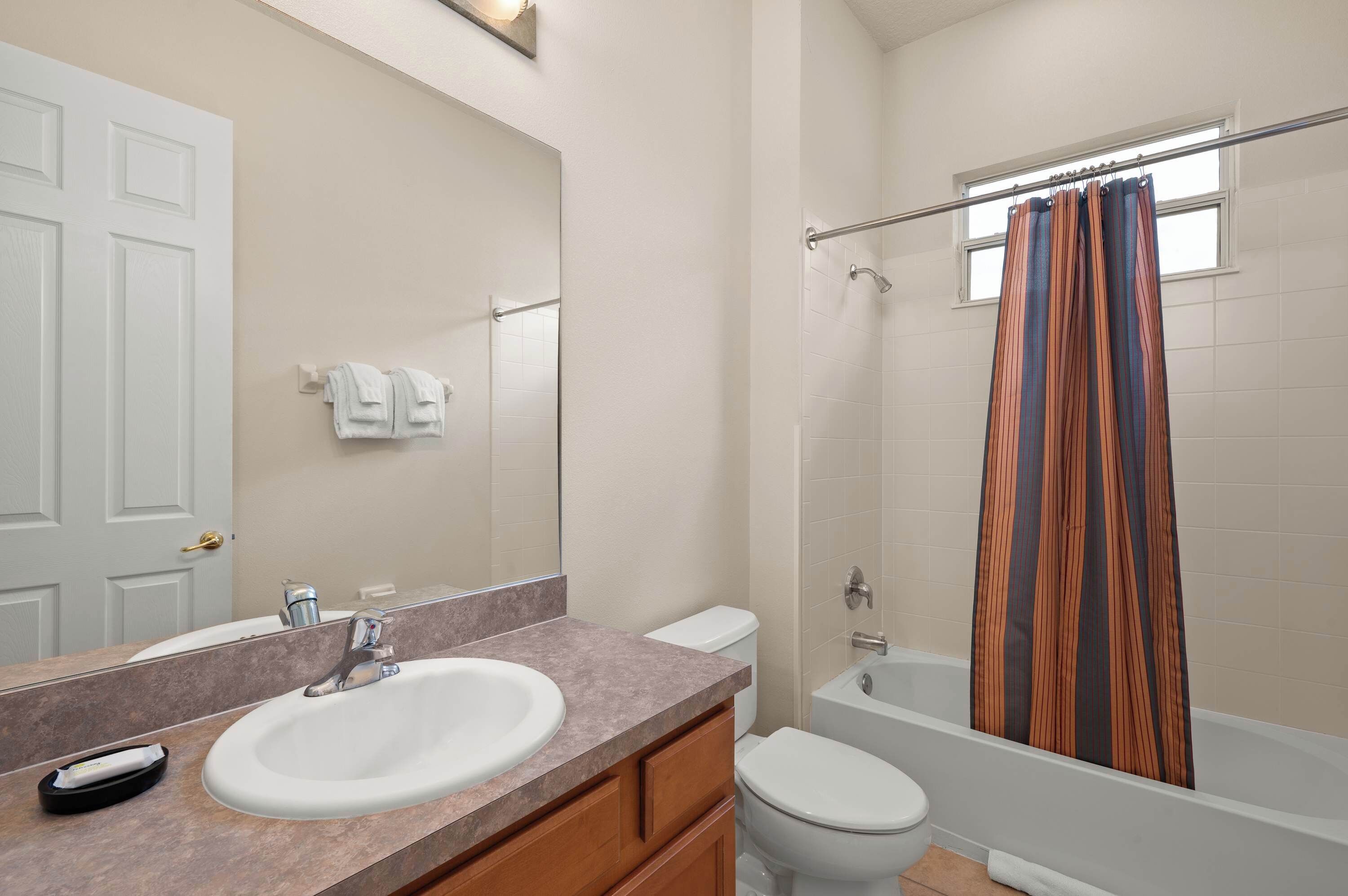 Een badkamer met een wastafel, spiegel, toilet en douche.