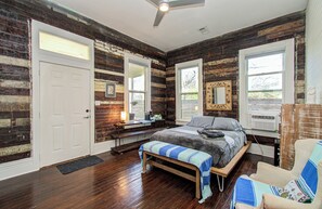 Ein Schlafzimmer mit Bett, Bank, Stuhl und Deckenventilator.