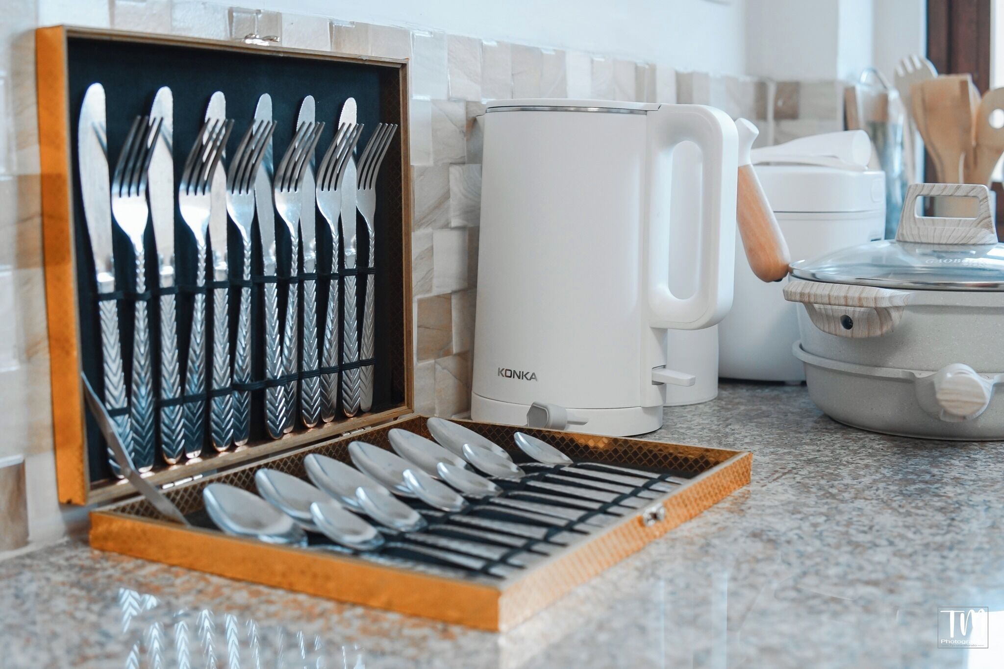 Una encimera de cocina con un juego de cubiertos en una caja de madera, una cafetera Konka blanca y un hervidor eléctrico blanco.