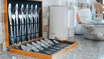 Una encimera de cocina con un juego de cubiertos en una caja de madera, una cafetera Konka blanca y un hervidor eléctrico blanco.
