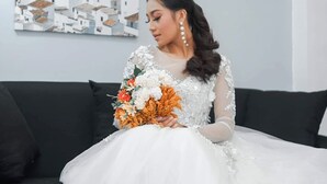 A person seated on a black sofa in a room with white walls and a framed artwork depicting white buildings. - Woodlands Condotel (Bulan)