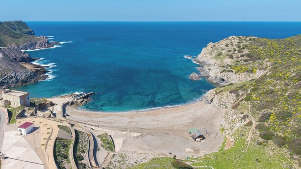 Un paysage côtier offrant une vue dégagée sur l’océan, avec un terrain rocheux et une zone aménagée avec des bâtiments.