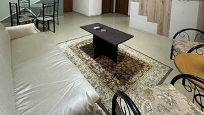 A living room with a sofa, a coffee table, a TV, and a staircase leading to another room. - Al Majd Hotel  (Amman)