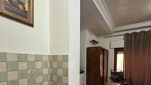 A kitchen with a granite countertop, stainless steel sink, and a tiled backsplash. There is a framed picture on the wall and a dining area with a table and chairs. - Al Majd Hotel  (Amman)