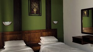 A hotel room with two beds, a wooden headboard, green walls, and a mirror on the right. - Al Majd Hotel  (Amman)