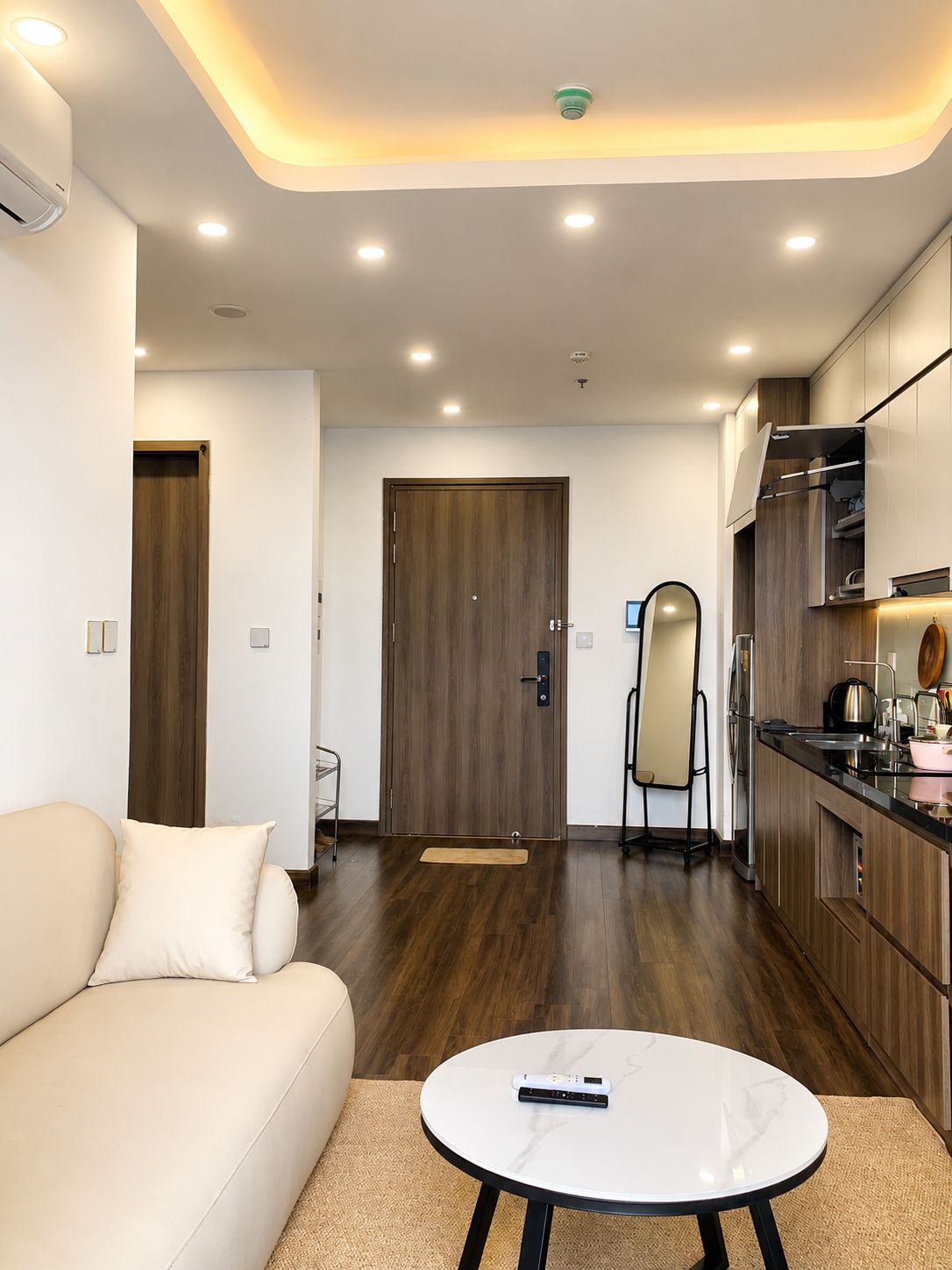 A modern living room with a sofa, a coffee table, and a kitchen area with cabinets and a countertop.