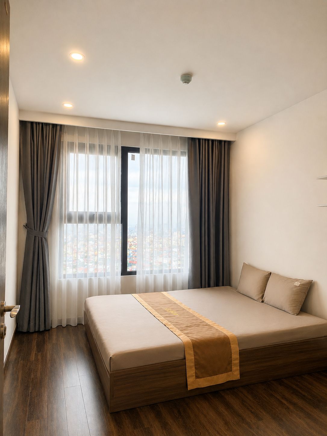 A hotel room with a large bed, a view of the city through the window, and a modern design.