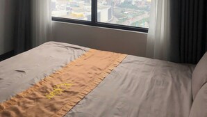 Ein Hotelzimmer mit großem Fenster, einem Bett und Vorhängen.