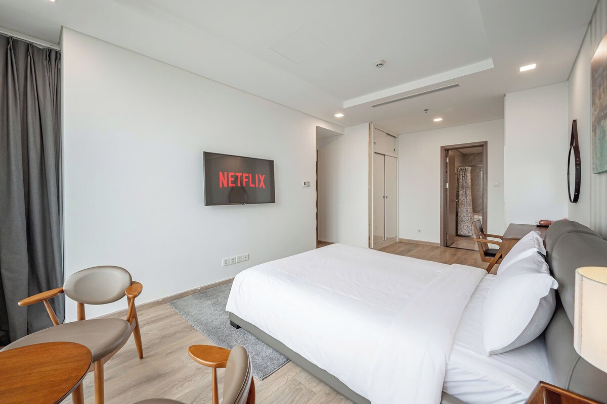 Une chambre d’hôtel moderne, dotée d’un grand lit, d’un téléviseur fixé au mur et d’un bureau avec une chaise.