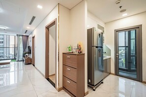 Une chambre d’hôtel moderne dotée d’une grande fenêtre, d’un minibar et d’une porte-fenêtre coulissante donnant sur un balcon.