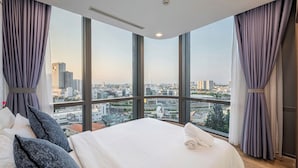 A hotel room with a large bed, a view of the cityscape through floor-to-ceiling windows, and a modern ceiling design. - LANDMARK 81 Signature Residence (Ho Chi Minh City)