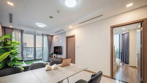 A modern hotel room with a dining area, a TV, and a balcony with a city view. - LANDMARK 81 Signature Residence (Ho Chi Minh City)