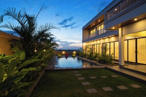 A modern building with a swimming pool, surrounded by lush greenery. - Pondok Uma Jero (Tabanan)