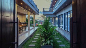 A modern building with a covered outdoor area, artificial grass, and potted plants. - Pondok Uma Jero (Tabanan)