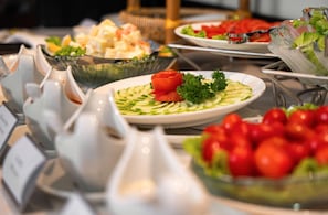 A buffet with various dishes, including salads and a bowl of cherry tomatoes. - Luxe Paradise Suites Hotel & Spa (Hanoi)