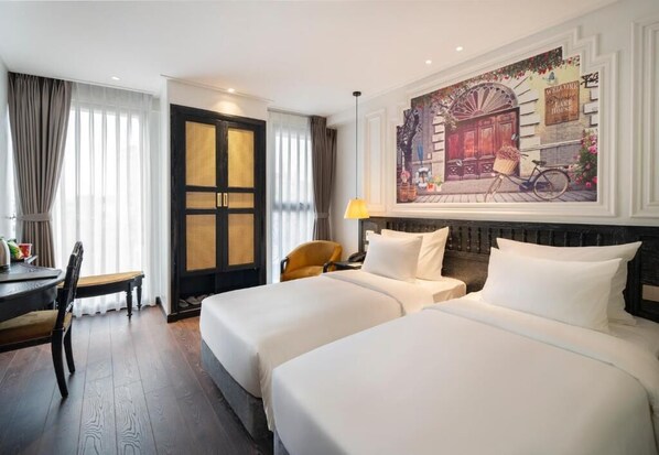 A hotel room with two beds, a dining table, a chair, a lamp, and a painting on the wall. - Luxe Paradise Suites Hotel & Spa (Ba Dinh)