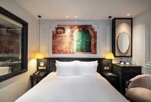 A hotel room with a large bed, two bedside tables with lamps, a mirror, and a wall-mounted artwork of a door. - Luxe Paradise Suites Hotel & Spa (Ba Dinh)