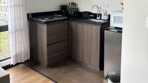 A modern kitchen with dark wood cabinets, a built-in stove, and a microwave.