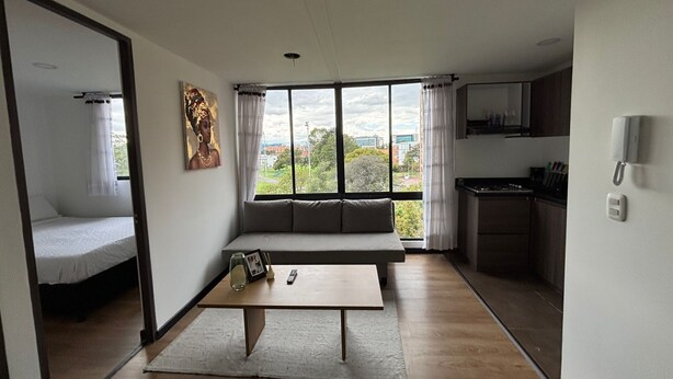 A compact living space with a bed, a sofa, a dining table, and a kitchen area.