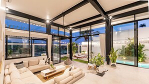 A modern living room with a large sofa, a coffee table, and a view of a pool and outdoor seating area. - Villa Bali Escape– Private Ricefield Retreat, Steps from the Canggu Action (Canggu)