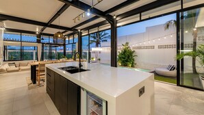 A modern kitchen with a large island, built-in appliances, and a view of the outdoor patio area. - Villa Bali Escape– Private Ricefield Retreat, Steps from the Canggu Action (Canggu)