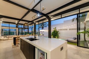 A modern kitchen with a large island, built-in appliances, and a view of the outdoor patio area. - Villa Bali Escape– Private Ricefield Retreat, Steps from the Canggu Action (Canggu)