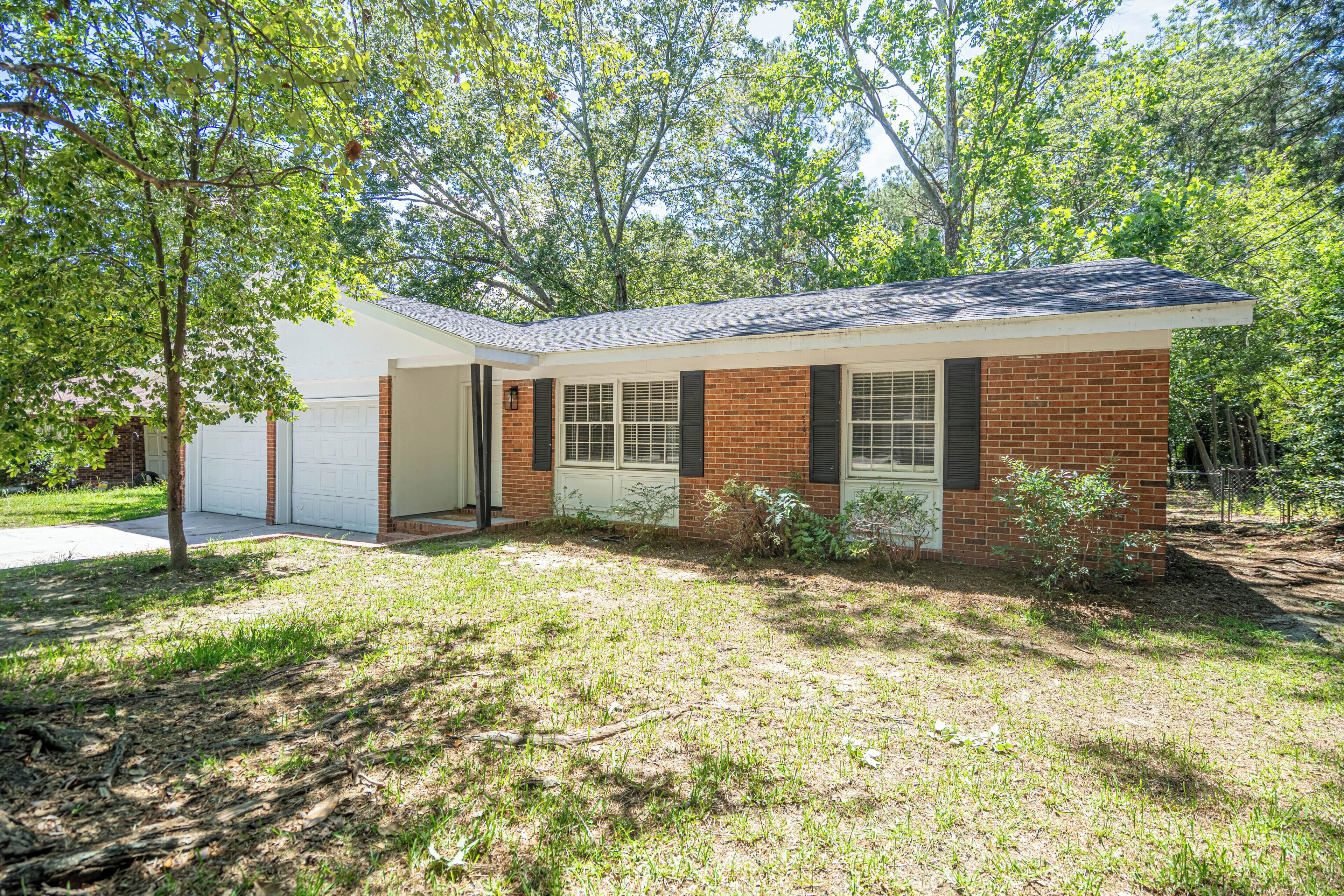 A single-story house with a garage, a brick exterior, and a lawn.