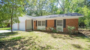 A single-story house with a garage, a brick exterior, and a lawn.