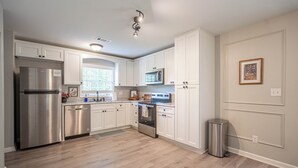 A modern kitchen with white cabinets, stainless steel appliances, and a window providing natural light.
