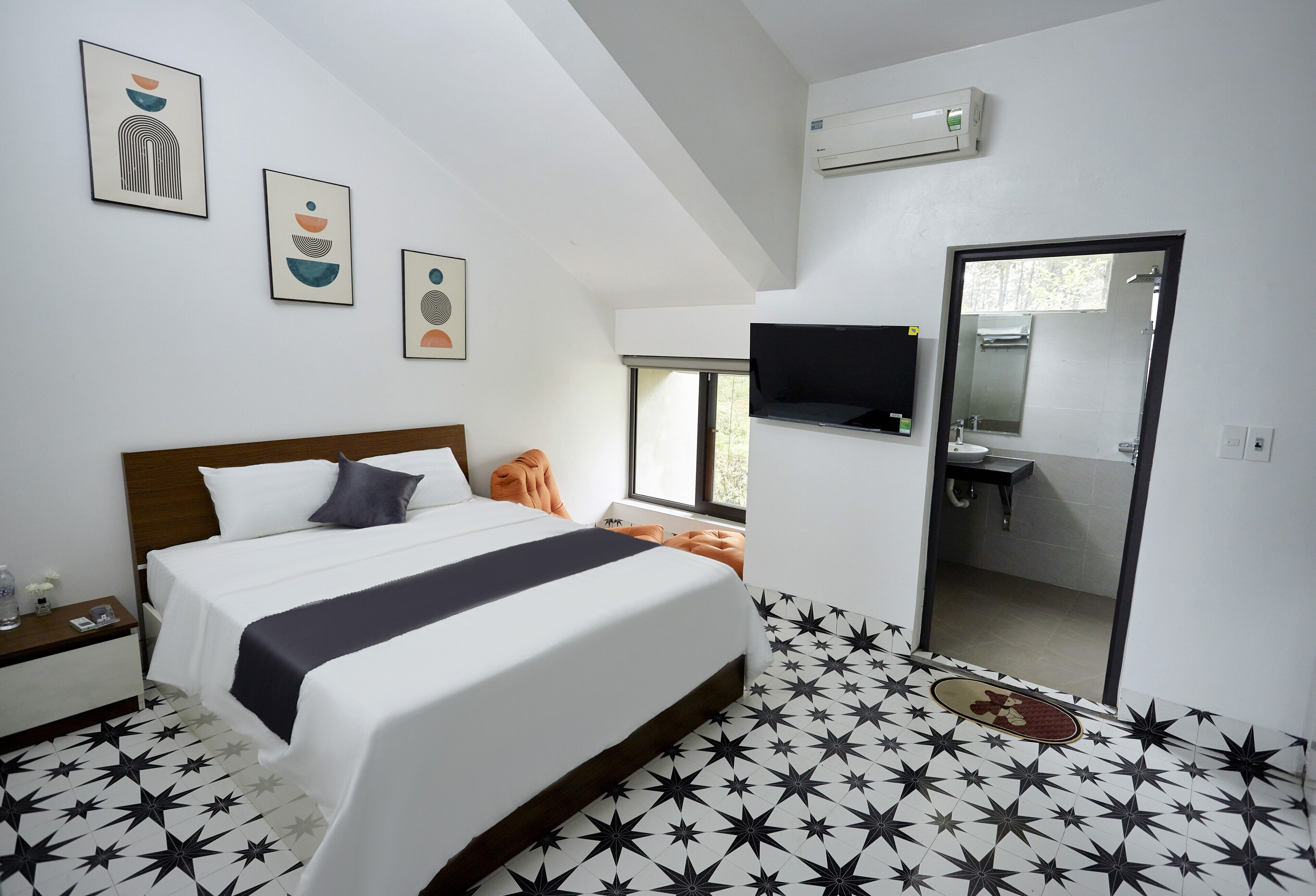 A modern hotel room with a large bed, a flat-screen TV, a bathroom with a mirror, and star-patterned flooring.