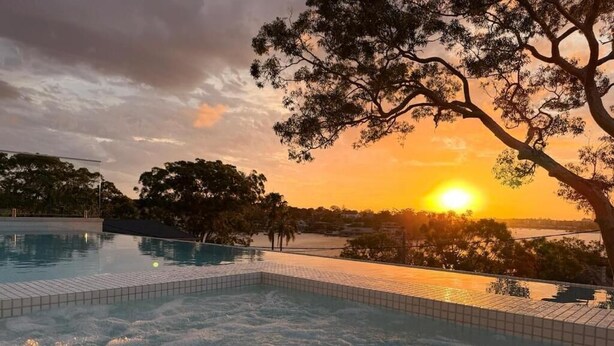 Una piscina amb vistes al capvespre i als arbres circumdants.