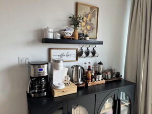A coffee station with a Keurig machine, a coffee maker, and various coffee-related items on a black countertop.