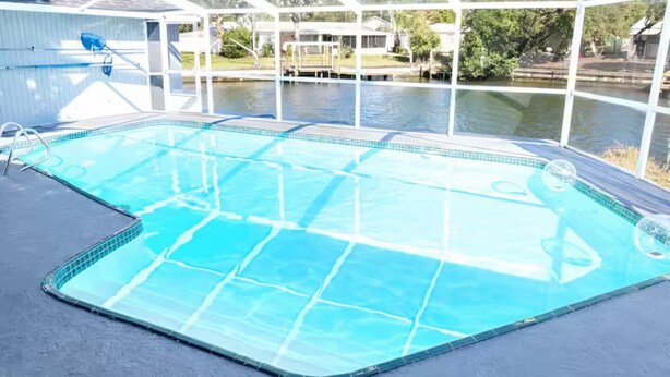 Ein Pool mit Blick auf ein Haus und Bäume, eingeschlossen durch Glas.
