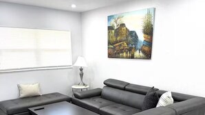 Ein modernes Wohnzimmer mit einer Eckcouch, einem Couchtisch und einem Gemälde an der Wand.