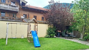 Una casa de madera con balcón, un columpio y un tobogán en el jardín.