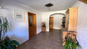 Un pasillo amplio con una puerta de madera, una pequeña mesa con flores y un armario.