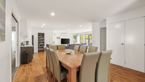 A modern kitchen with white cabinets, a dining area with a wooden table and chairs, and a living room with a sofa and TV. - Fireside Retreat in Cowes (Cowes)
