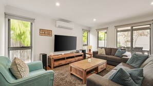 A living room with a large flat-screen TV, wooden entertainment unit, and two sofas. - Fireside Retreat in Cowes (Cowes)