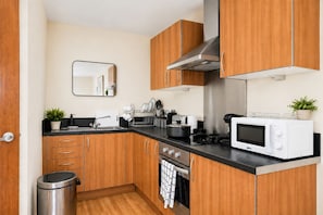 A compact kitchen with wooden cabinets, a stainless steel range hood, a microwave, and a sink. - Central Birmingham •Free Parking •City Views (Birmingham)