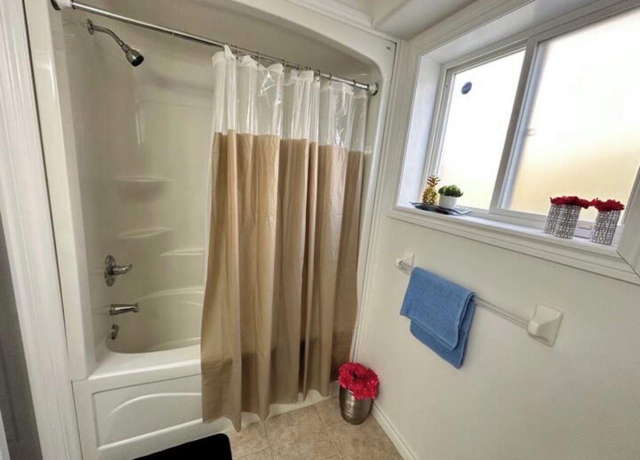Une salle de bain avec une baignoire, un rideau de douche, une fenêtre avec vue et un porte-serviettes.