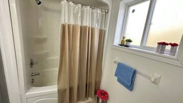 Une salle de bain avec une baignoire, un rideau de douche, une fenêtre avec vue et un porte-serviettes.