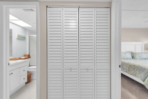 A bedroom with a bed, a white closet, and a bathroom with a toilet and sink. - Bayshore Yacht & Tennis 211 - Premier (Indian Shores)
