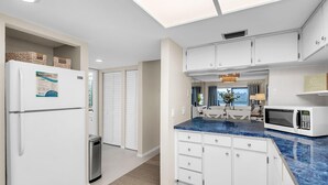 Una cocina moderna con gabinetes blancos, encimera azul y microondas integrado.