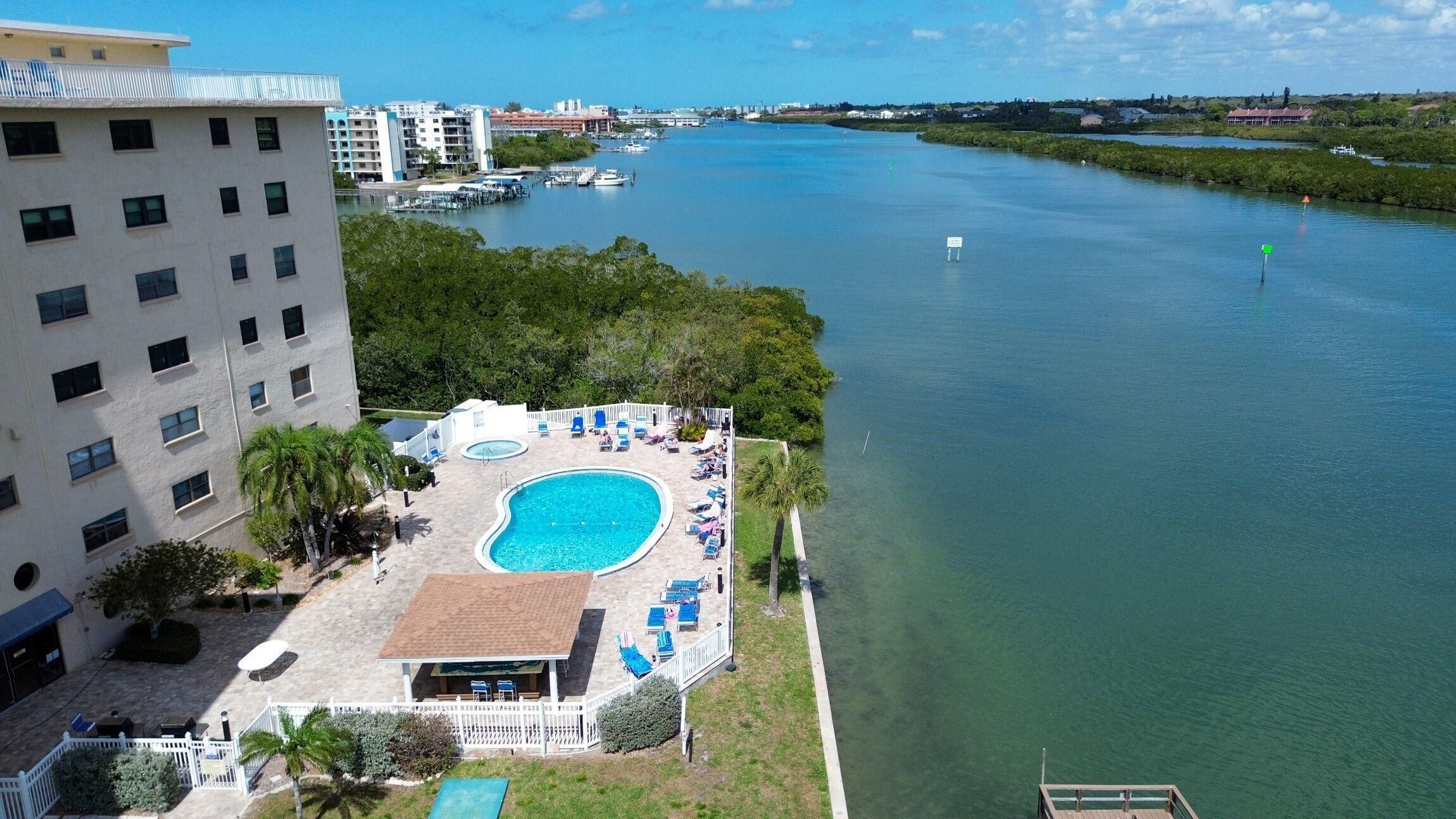 Um hotel com piscina, vista para a água e um edifício ao fundo.