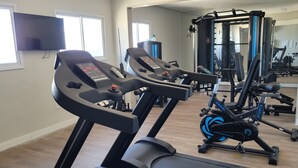 Een fitnessruimte met loopbanden, een hometrainer en krachttoestellen.