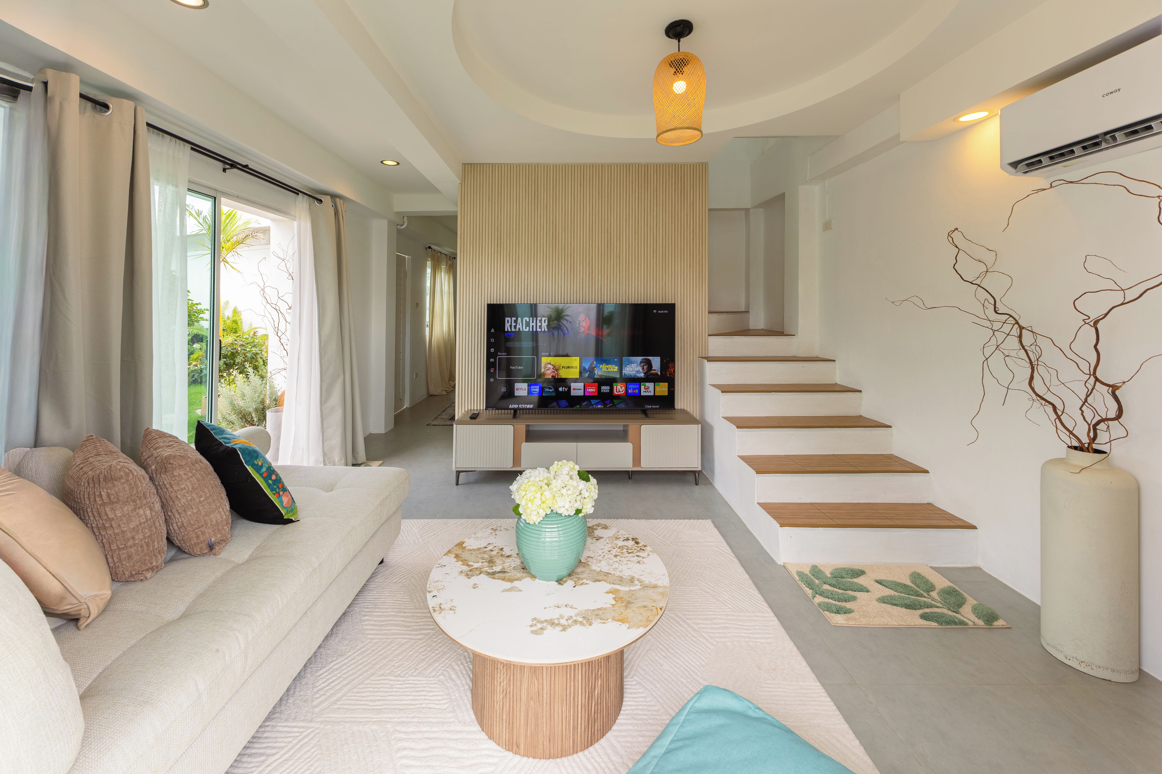 Una sala de estar moderna con un sofá, una mesa de centro, un televisor y una escalera.